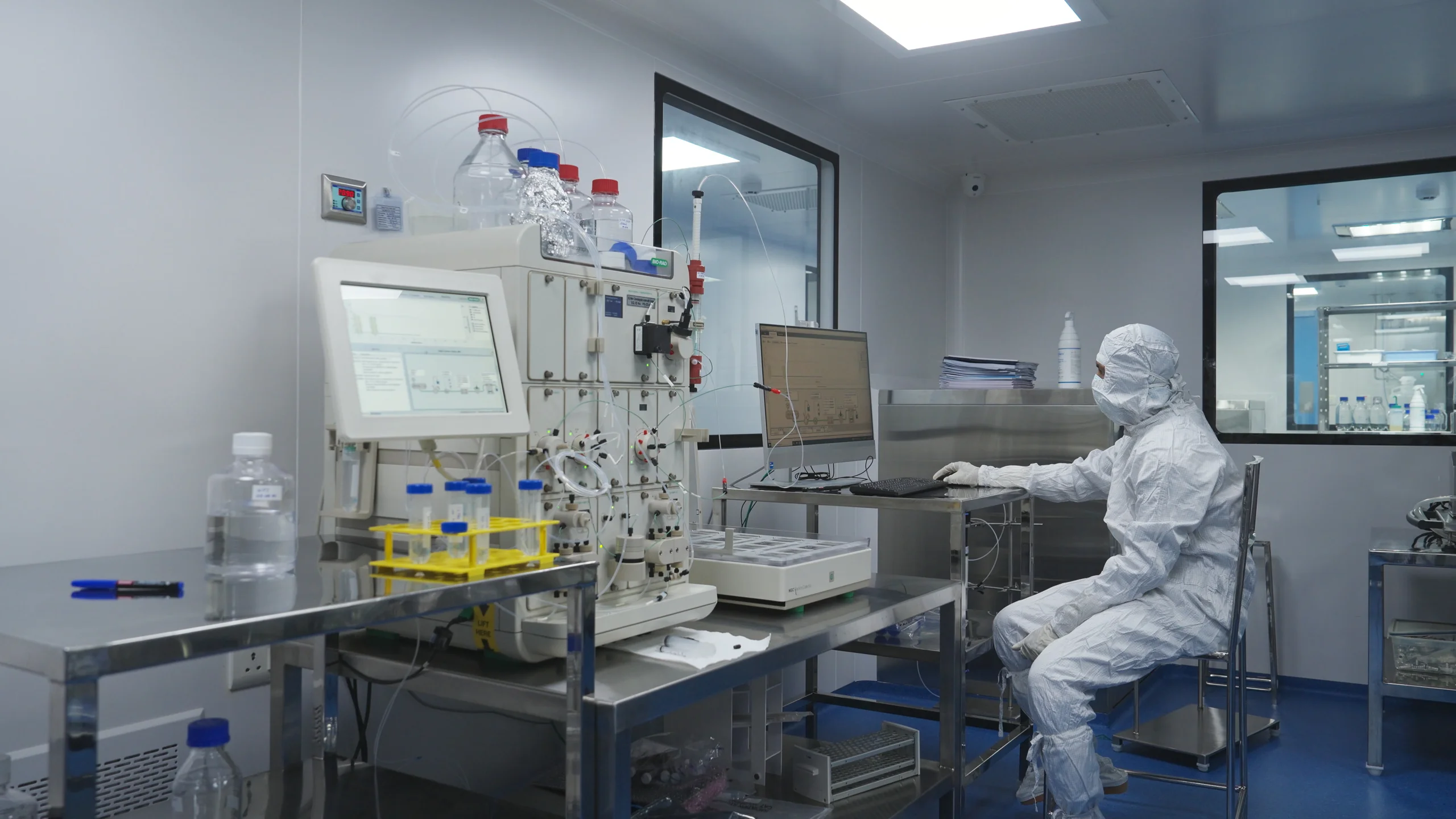 An operator running a chromatography system in a cleanroom at the RNA Foundry.
